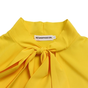 Dettaglio dello scollo di un abito giallo brillante con elegante fiocco e etichetta