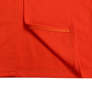 Detail of double-needle stitching and overlock seams on bright orange pleated knit dress