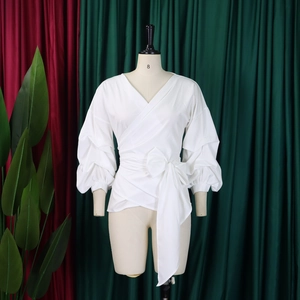 Detail of white wrap shirt showing V-neckline, puff sleeves, and waist tie ribbon