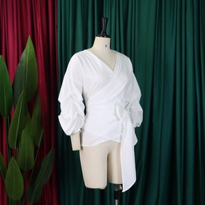 Detail of white wrap shirt featuring lantern sleeves and adjustable waist tie belt