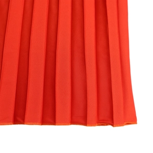 Close-up of bright orange pleated dress hem with fine accordion folds and stitching