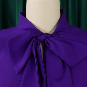 Close-up of deep purple blouse featuring elegant bow-tie neckline and textured fabric