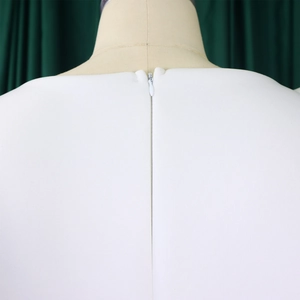 Détail d'une robe de soirée blanche avec fermeture éclair invisible et coutures de précision