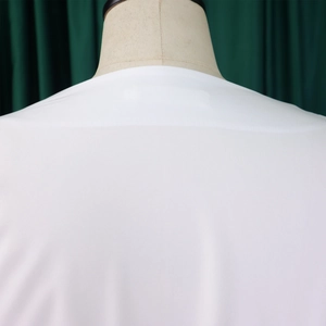 Detail of white cross-strap blouse showing the V-neckline and puffed sleeve on a mannequin
