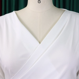 Detail of white V-neck wrap top showing light fabric texture and clean cross stitching