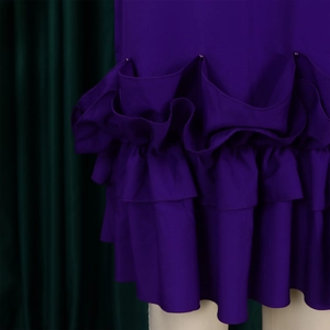 Detailed view of dark purple dress featuring layered ruffles and elegant pearl accents