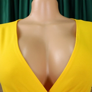 Detail of deep V-neckline and tailored shoulder structure on bright yellow dress