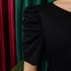 Detail shot of black elegant dress featuring textured pleated puff sleeves and fabric texture