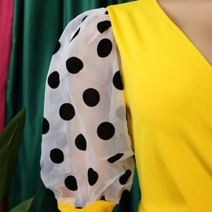 Detail of V-neck yellow dress with sheer puff sleeves and black polka dot pattern