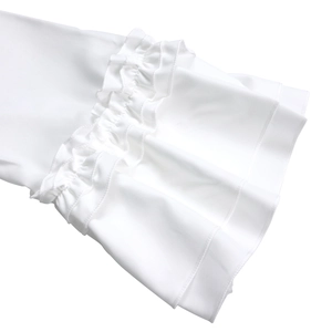 Dettaglio dei polsini svasati bianchi eleganti e del bordo a balze del vestito