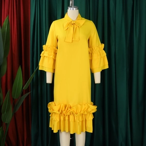 Detail of elegant yellow midi dress featuring bow tie neckline and tiered ruffle sleeves