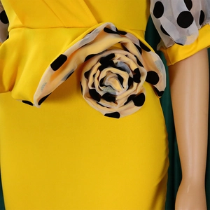 Detailed close-up of 3D floral accent and polka dot mesh puff sleeves on yellow dress