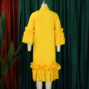 Detail view of bright yellow dress with multi-layer ruffle cuffs and a pleated hemline