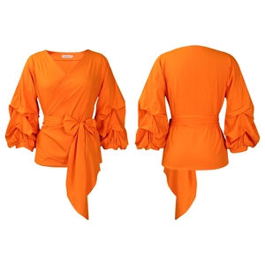 Detail of orange V-neck wrap top featuring unique layered puff sleeves and waist tie