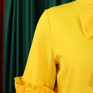 Detail of yellow dress featuring elegant ruffle bell sleeves and smooth fabric texture