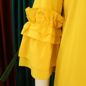 Detailed macro view of the layered ruffle sleeve on a bright yellow summer dress fabric
