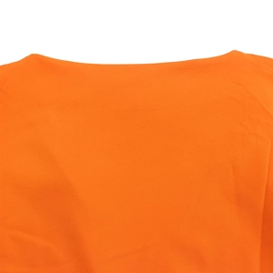Detailed close-up of vibrant orange fabric featuring elegant cross-strap off-shoulder design
