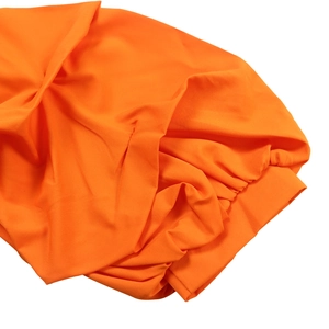 Detailed close-up of orange off-shoulder blouse fabric showing elastic cuffs and texture