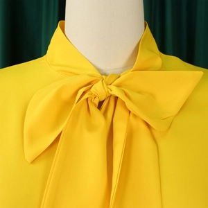 Detail of elegant pussy bow neckline on a bright yellow ruffle sleeve dress