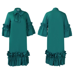 Detail view of dark green long sleeve dress showing ruffled sleeves and bow tie neckline