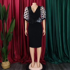 Detail of V-neck pencil dress featuring mesh polka dot sleeves and a 3D floral accent