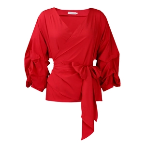 Detail of red wrap shirt featuring pleated puff sleeves and a chic waist tie bow