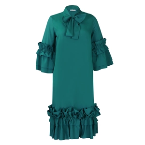 Detail of teal green dress featuring bow neckline and triple-layered ruffle sleeves