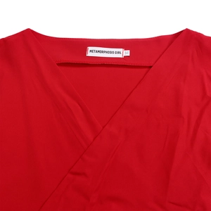 Close-up of red V-neck cross strap design with a woven size M label on textured fabric