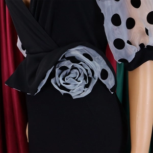 Detail of elegant black dress featuring a mesh polka dot floral waist ornament and cuffs