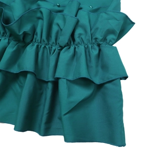 Close-up of emerald green dress with layered ruffles and delicate beadwork detailing