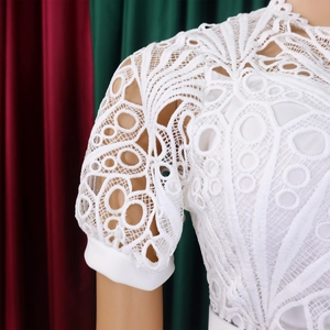 Close-up of white lace dress featuring intricate floral hollow-out embroidery and high neck