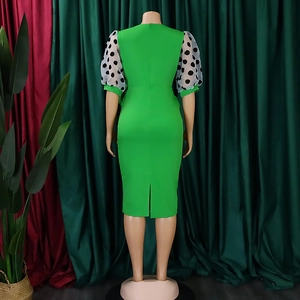 Detail of green pencil dress featuring sheer polka dot puff sleeves and back slit hemline