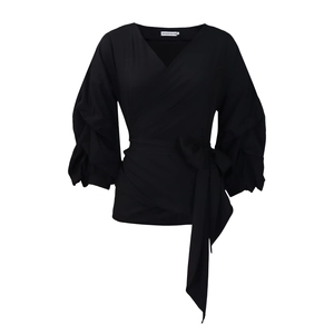 Detail of black wrap blouse featuring deep V-neck, puff sleeves and waist tie design