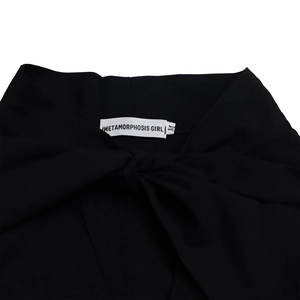 Macro view of neck label with METAMORPHOSIS GIRL logo and size M on black dress