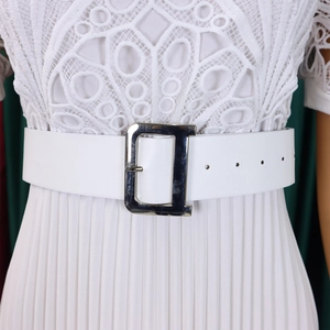 Close-up of white lace bodice with pleated skirt and metallic D-buckle belt detail