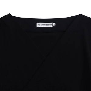 Detail of V-neckline with brand label on a black puff sleeve shirt for women