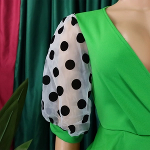 Detail of bright green dress featuring polka dot sheer mesh puff sleeves and V-neckline