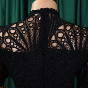 Detail of delicate black lace dress featuring geometric hollow patterns and hidden zipper