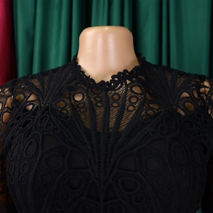 Close-up of intricate lace neckline and geometric floral patterns on a black dress