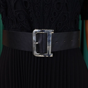 Close-up of a black leather belt featuring a large silver metal D-shaped buckle for dresses