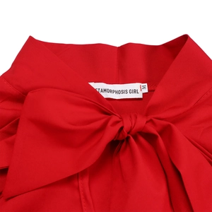 Detail shot of a red dress featuring a large bow and size M label on white background