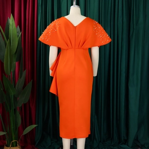 Detail van een oranje jurk met blote rug, witte parels en geplooide ruches op een etalagepop
