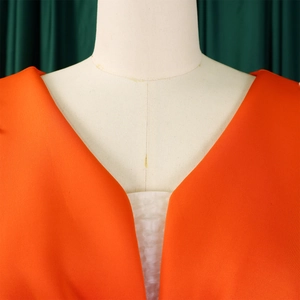 Detailopname van de elegante V-hals en de oranje stoftextuur van de modieuze jurk