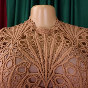 Close-up of intricate lace neckline and geometric hollow weaving on mauve dress