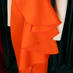 Detail van gelaagde ruffles en dikke gestructureerde stof op een oranje avondjurk