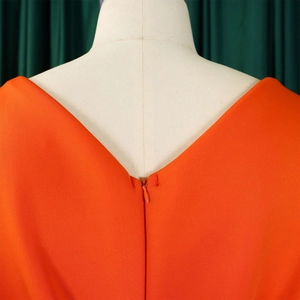 Detail van de oranje avondjurk met een diepe V-hals op de rug en een verborgen ritssluiting