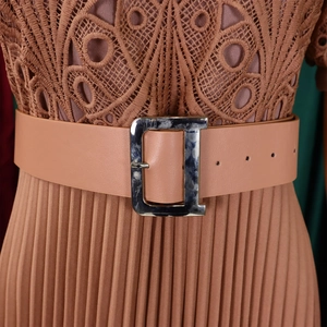 Detail of lace bodice and pleated skirt with D-buckle leather belt in dusty rose