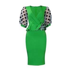 Détail de robe verte col V avec manches bouffantes en tulle à pois et fleur à la taille