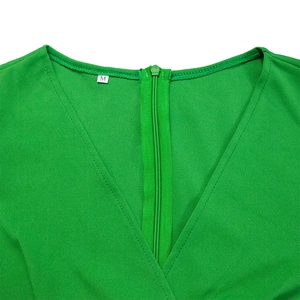 Détail de la robe verte avec col en V, fermeture éclair invisible et étiquette de taille M