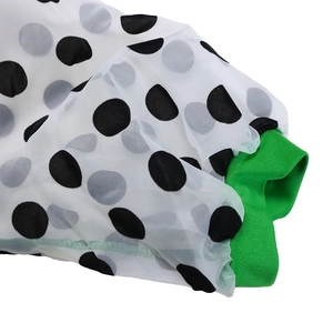 Détail du tissu en mousseline blanche à pois avec poignet en tricot côtelé vert vif